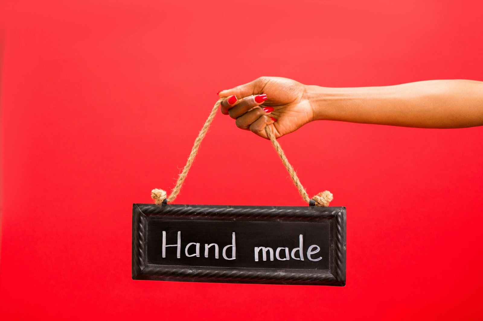 A handmade sign held by a woman against a vibrant red background symbolizing craftsmanship.