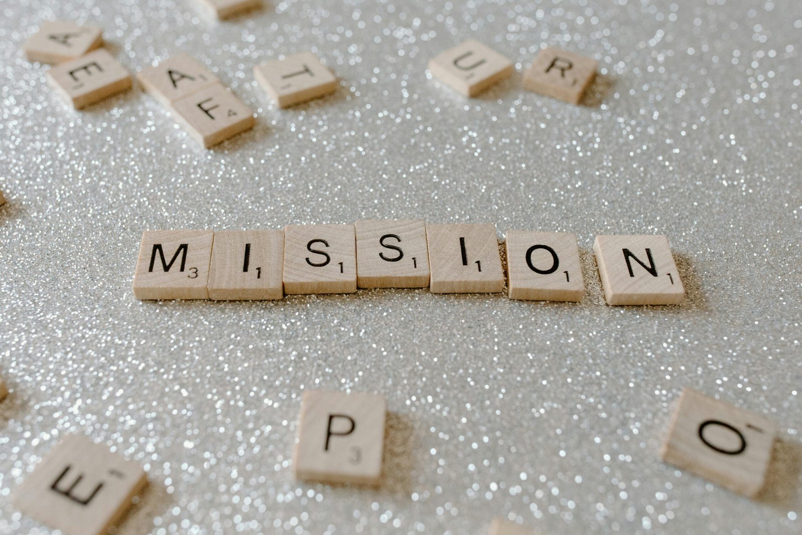 Scrabble tiles spelling 'Mission' on a sparkling surface convey determination and goals.